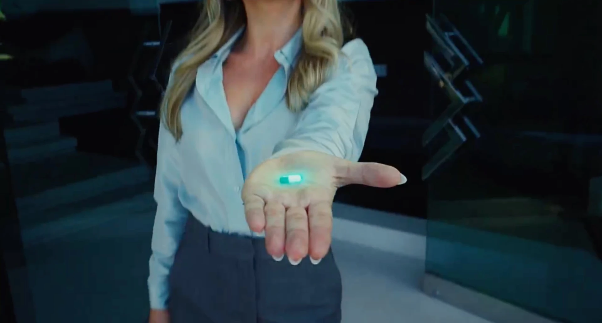 A woman holding out a glowing green pill in her open hand